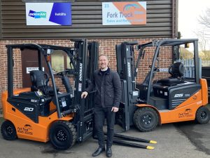 5000th Truck Rental Donated to Ben - Dave Brown in front of 2 forktrucks outside Fork Truck Direct Ltd