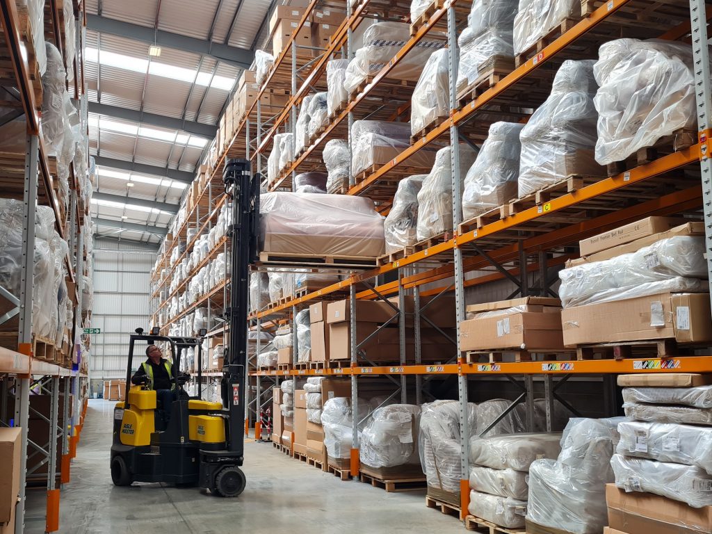 HSL Chairs - forklift lifting a sofa onto high warehouse storage unit