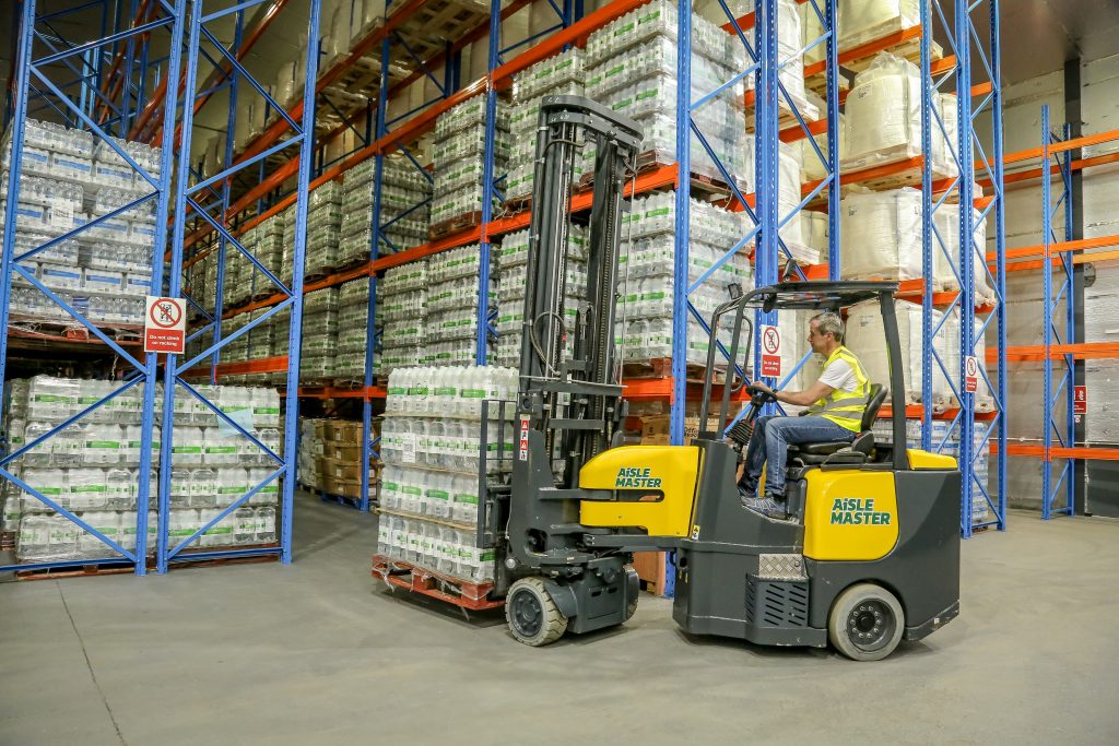 Combilift investment - Aisle Master carrying water bottles down narrow aisle in warehouse